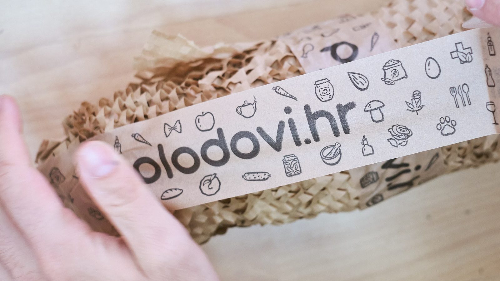 A parcel being sealed with Plodovi.hr branded tape over honeycomb paper wrapping.